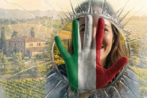 Dłoń pomalowana w barwy włoskiej flagi roztapia lód, otwierając widok na słoneczną Toskanię. Metafora przełamania bariery językowej na wiosennych kursach włoskiego online w Porto Felice.